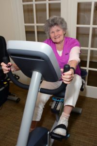 Resident Joann Joyce gets into the spirit of the new Fitness Center as she takes a turn on the recumbent elliptical.