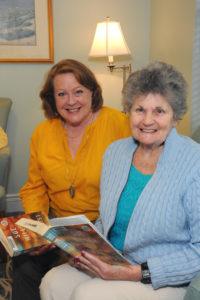 Activity Assistant Janeen Culhane and resident Joanne Joyce look up for a moment as they peruse a Book Club selection