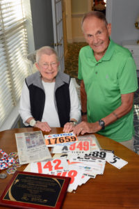 Marathoner Herman Messmer and Allerton House resident Marilyn Johnson look over the many bib numbers from races he has run.