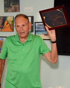 Hingham resident and veteran Herman Messmer holds up a Hingham Road Race plaque commending him for his years of commitment and service.