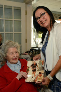Allerton House in Hingham Activity Director Kim Vallatini and resident Mary Lou Fitzsimmons look at a photo of Herman Messmer, taken during one of his many races.