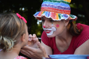 Clown doing face painting on a young child
