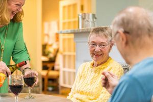 Retirees enjoying a glass of wine in a senior living apartment
