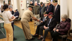 Director of Veterans’ Services Keith Jermyn presents a commemorative pin to former Chairman of the Hingham Veterans’ Council, David Sargent, during last week’s event. (Photo courtesy Town of Hingham)