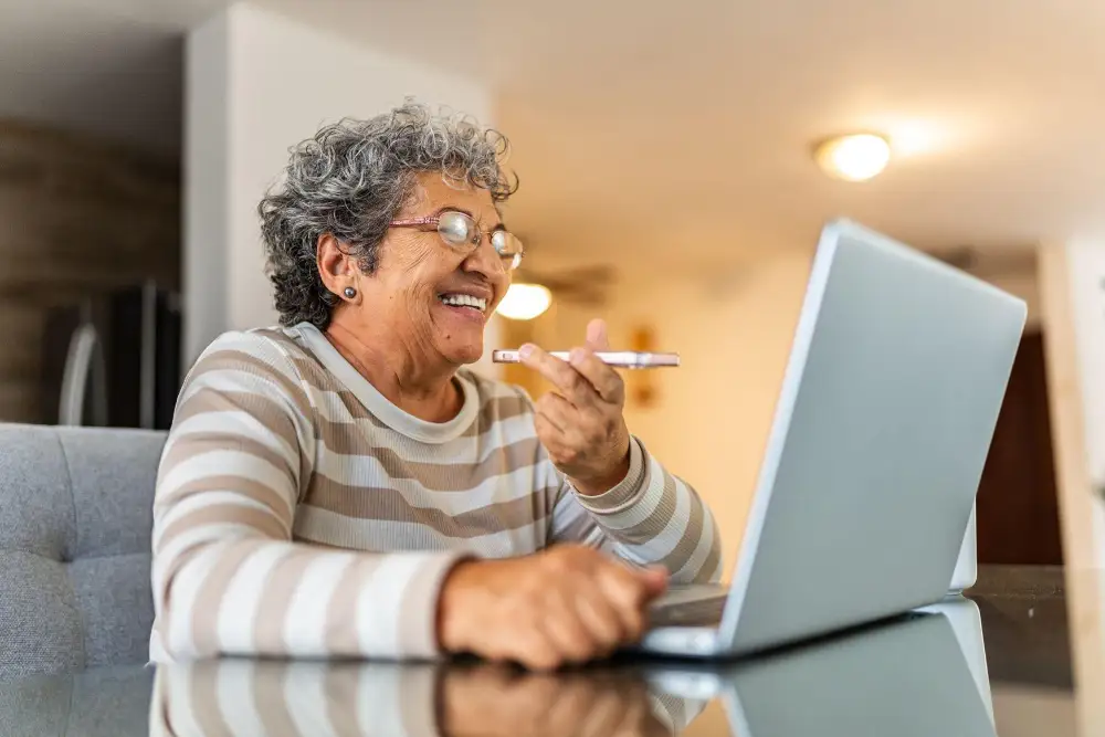 a senior woman talking on the phone while in front of her computer