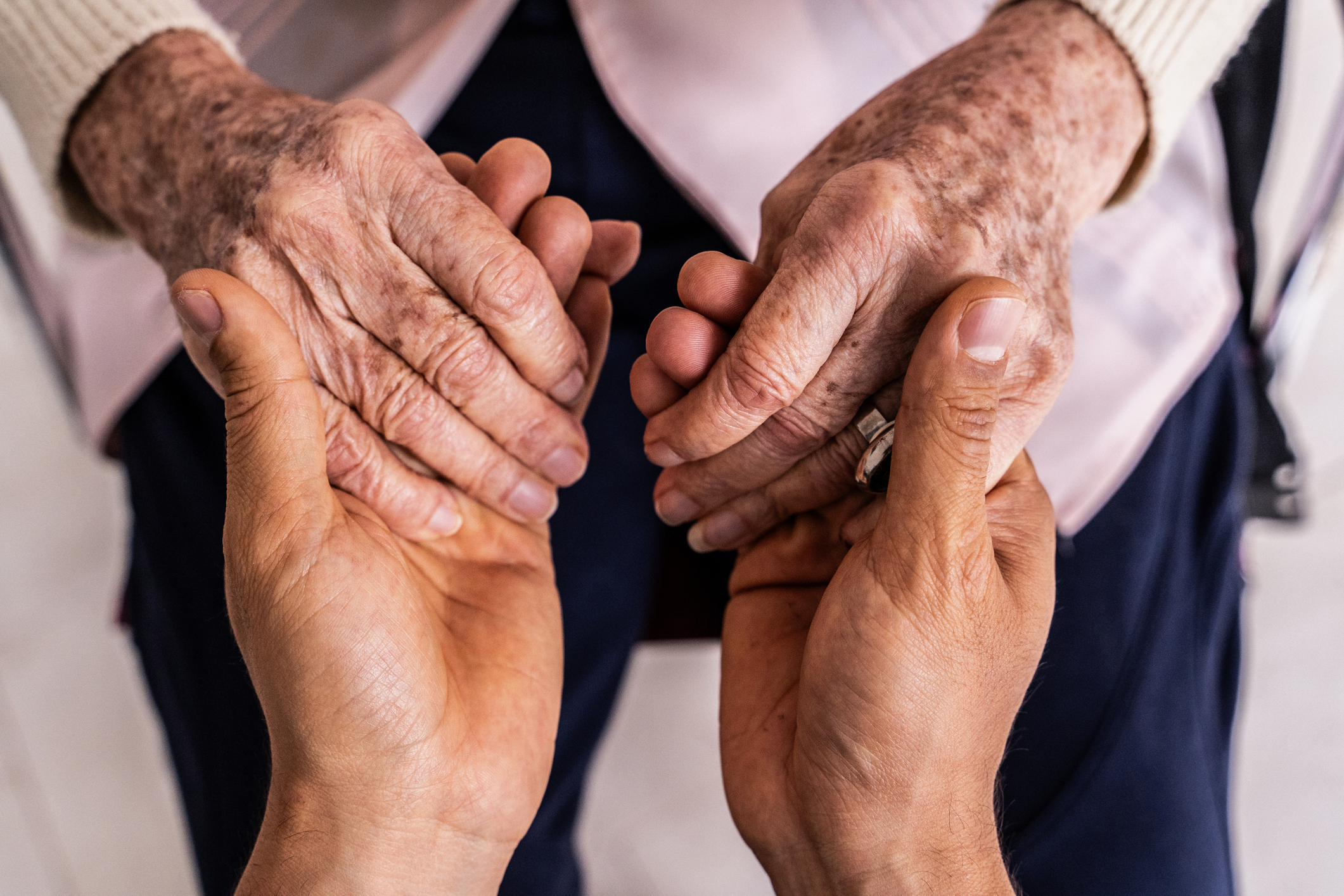 Close up of caregiver holding older person's hands
