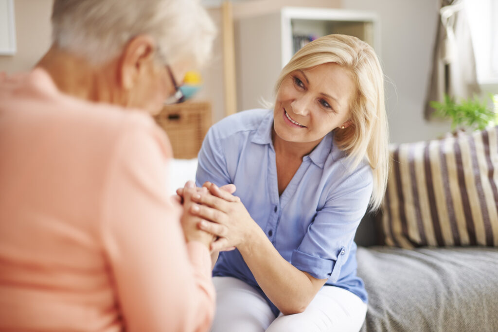 Adult woman comforting her senior mother on the couch