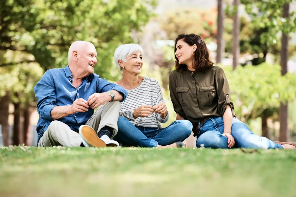 senior couple sitting with daughter in outdoor space