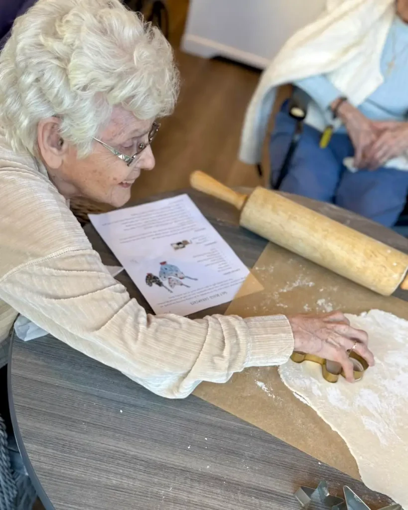 senior woman placing cookie cutter on dough, happy to participate in activities for seniors in assisted living